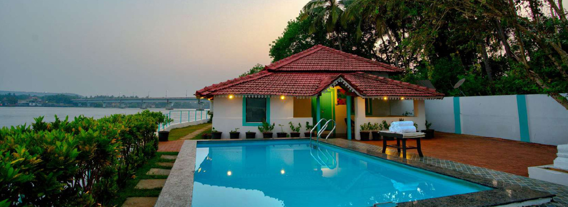 Private Goa villa with swimming pool, tiled roof, lush greenery and waterfront views