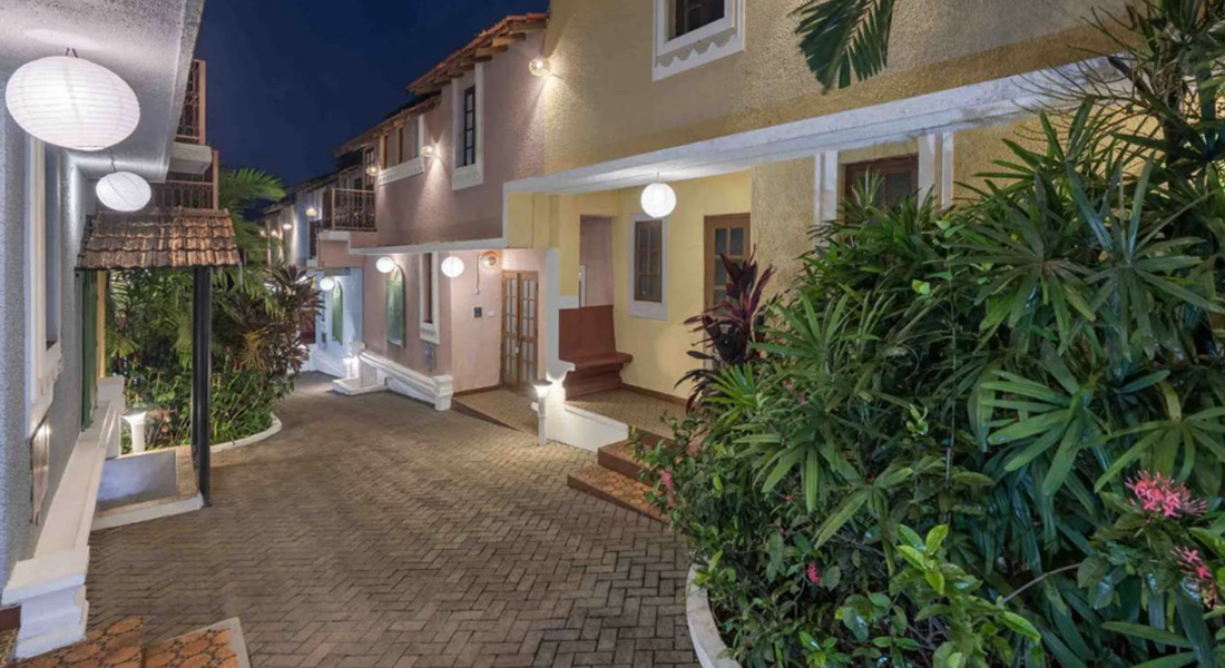 Portuguese-style villas courtyard with garden and pathway lighting at night in Goa