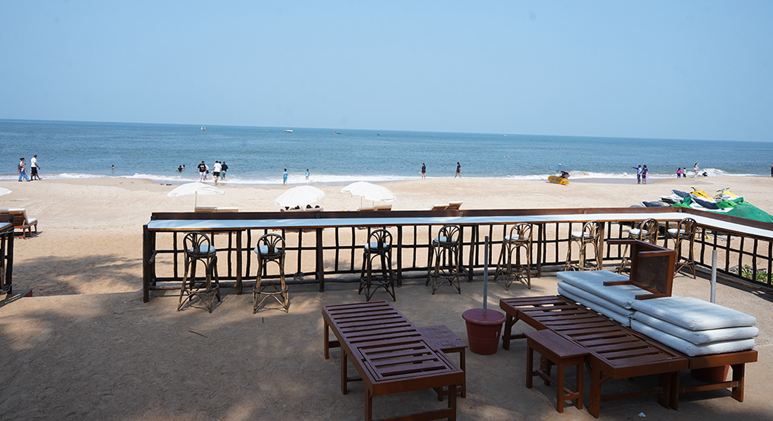 Beachside restaurant seating area with chairs and tables facing the arabian sea and sandy beach in goa