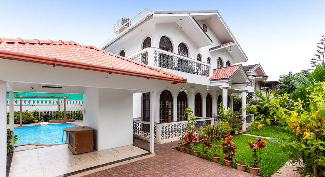 Two-storey white villa with red roof, arched balcony, and private swimming pool.