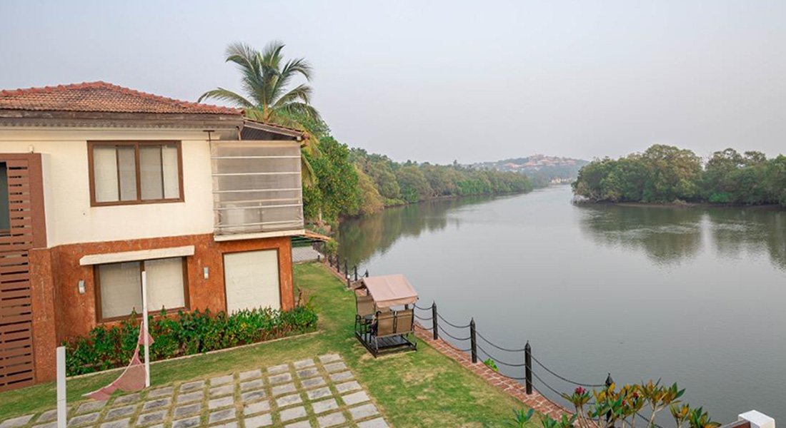 Luxury villa in Goa beside a calm riverside with garden seating and scenic tropical surroundings