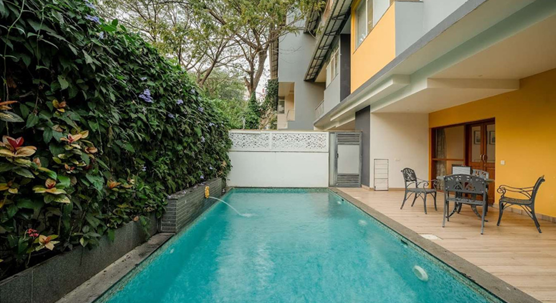 Modern villa with a private swimming pool, patio seating area, and lush vertical garden wall next to the pool.