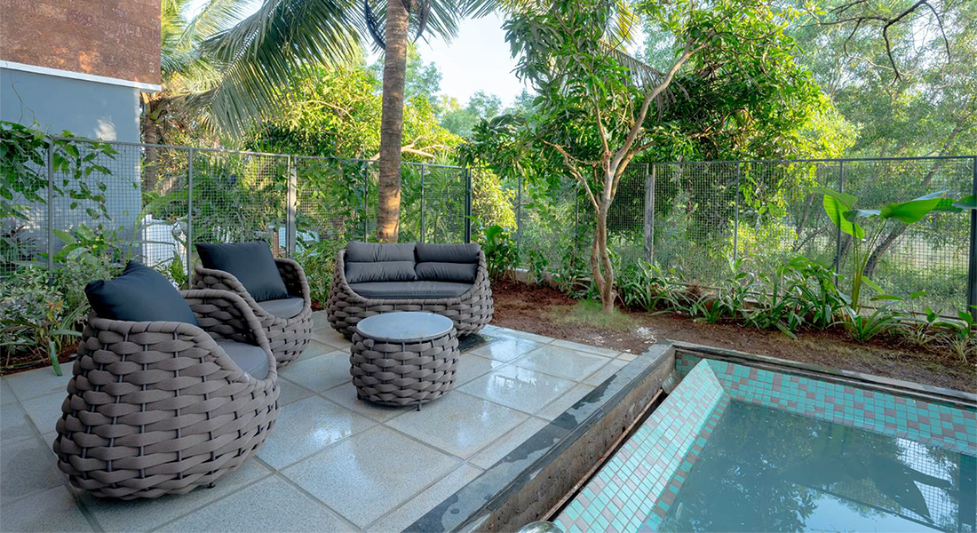 Private villa patio with woven outdoor seating and a small plunge pool surrounded by tropical trees and greenery