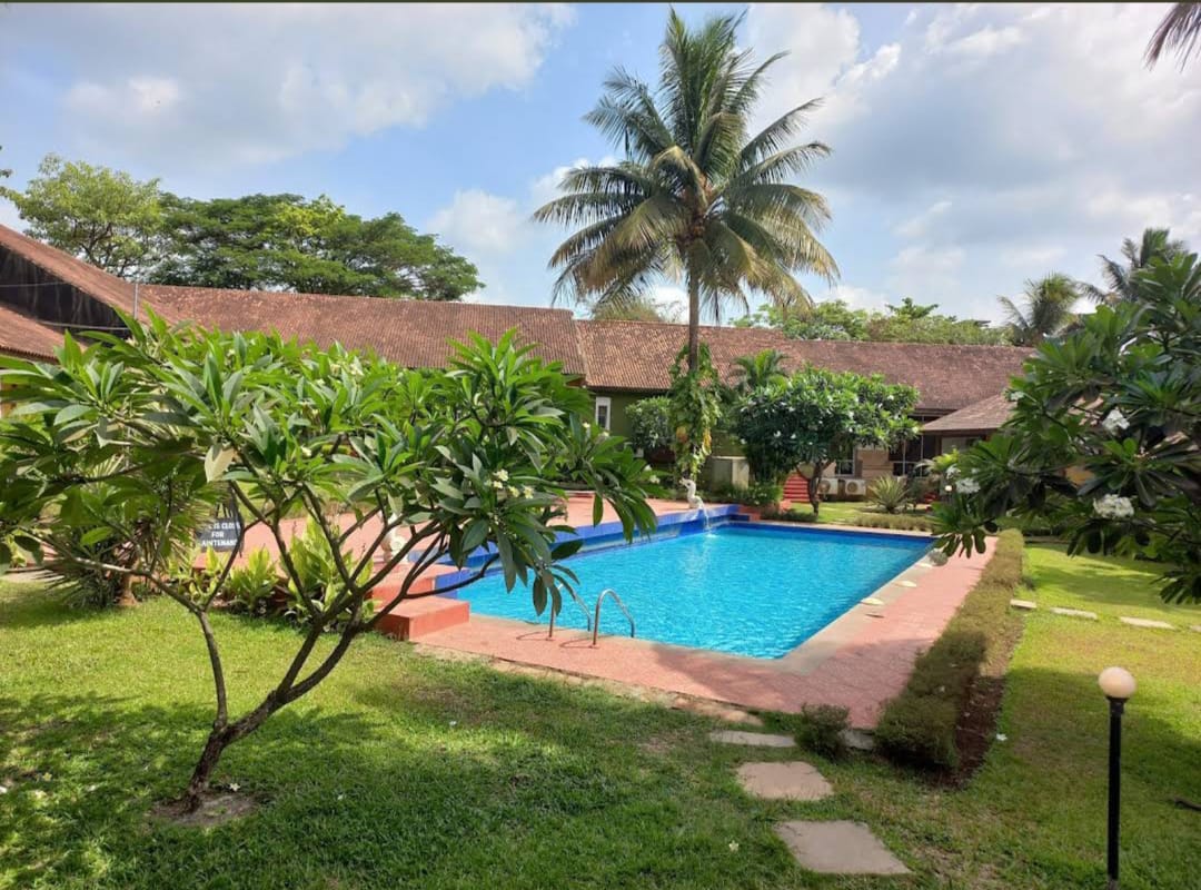 Swimming pool in a tropical garden with palm trees and villa buildings