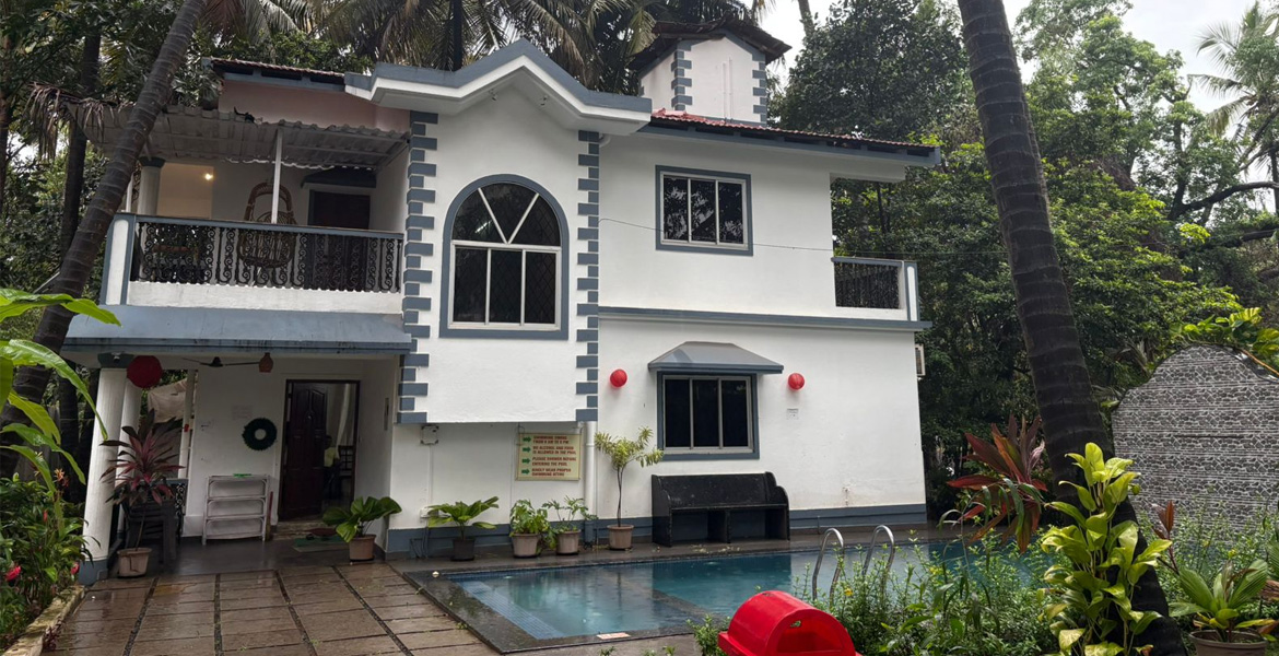 White private villa in Goa with swimming pool, balcony, and tropical coconut trees