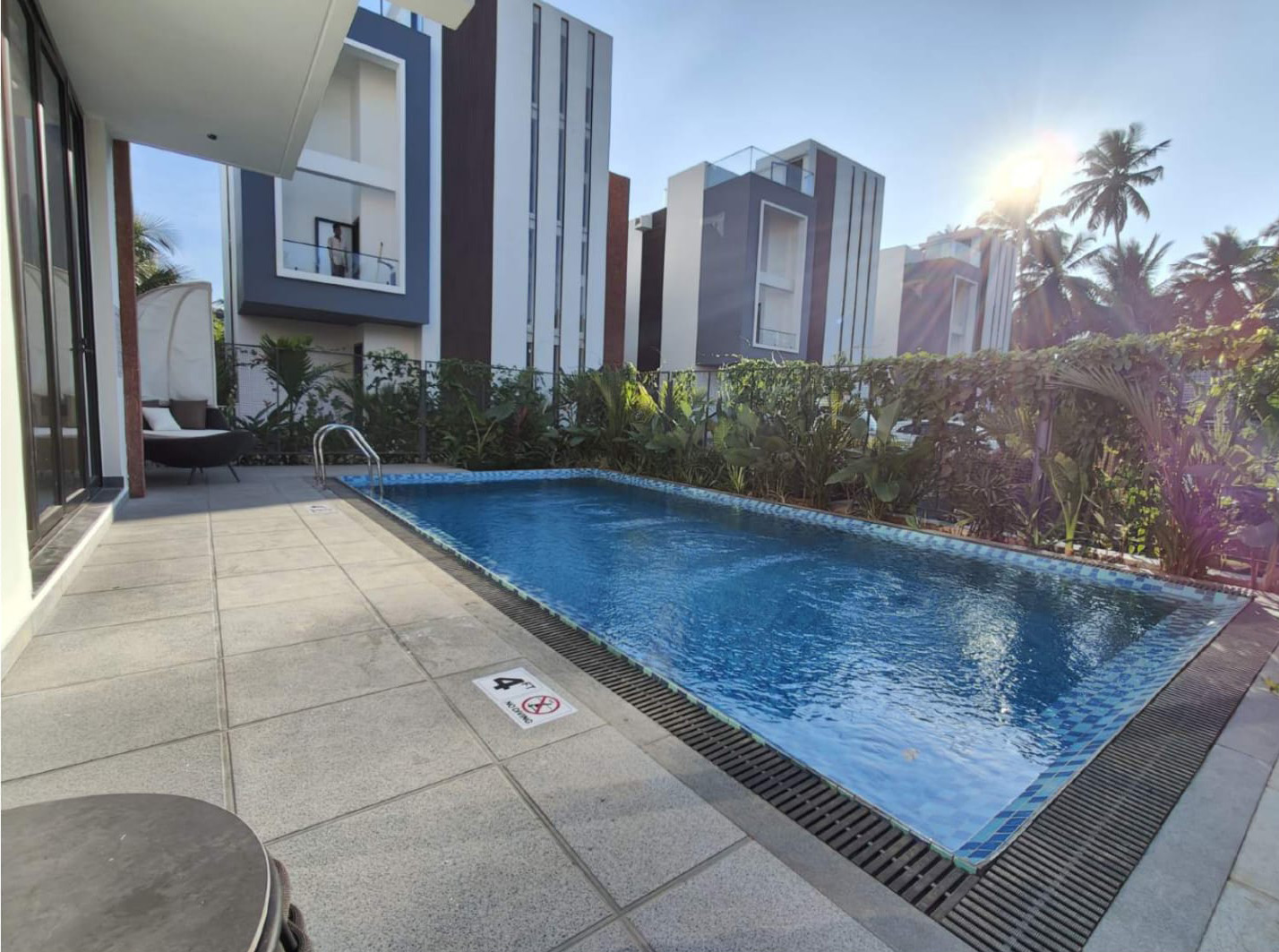 Exterior view of a modern villa and its private pool surrounded by greenery.