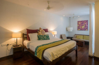 Villa bedroom with double bed, wooden floor, and sofa seating