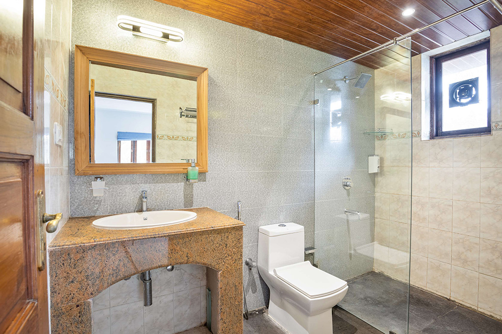 Bathroom with light tiles, granite vanity, and glass shower