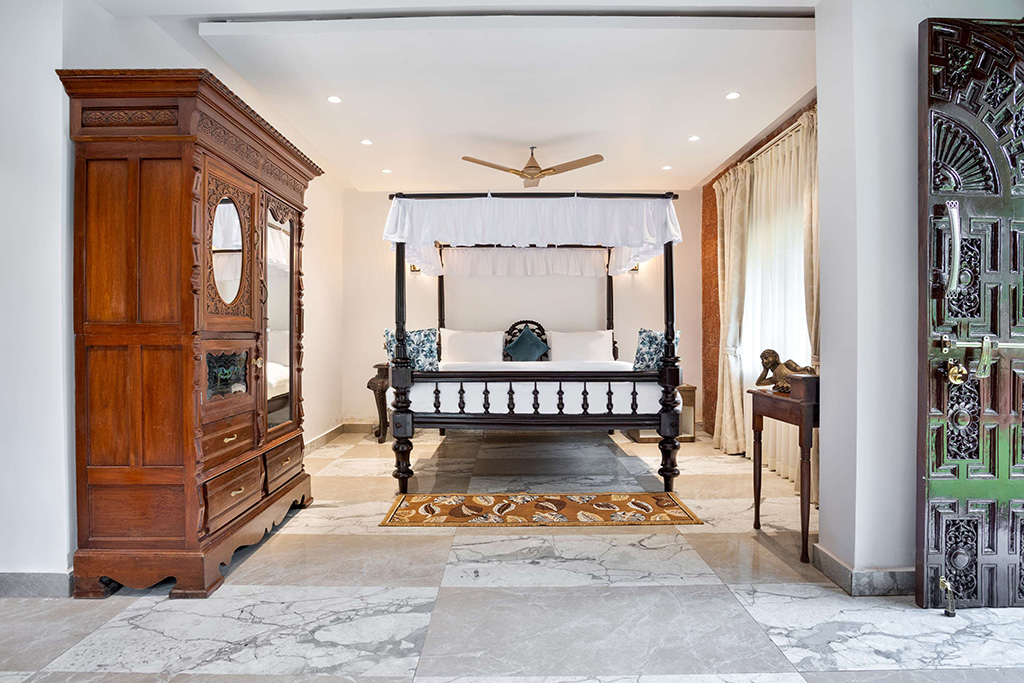 Four-poster bed and large wooden wardrobe in a white room