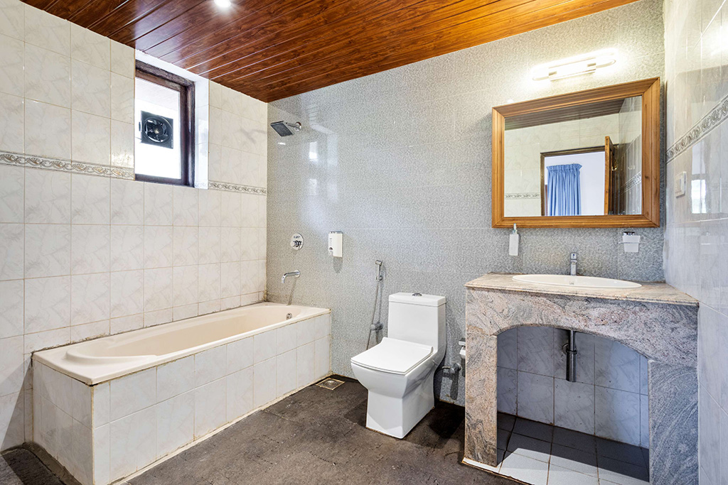 Bathroom featuring a built-in bathtub, white tiled walls, and a granite vanity with an arched opening
