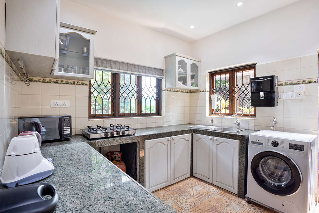 Functional kitchen with granite countertops, white cabinets, and a washing machine