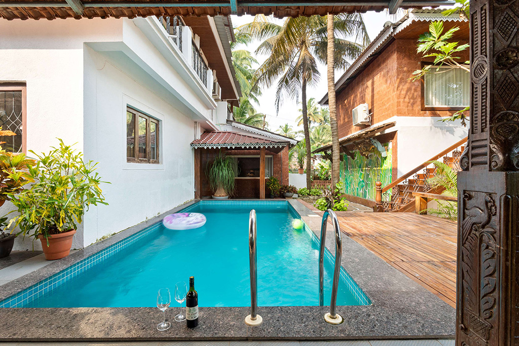Close-up of the private pool with wine glasses and a bottle on the edge, surrounded by tropical plants