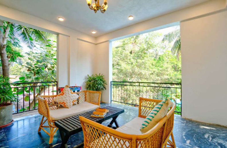 Balcony lounge seating with garden and palm tree view in Goa villa