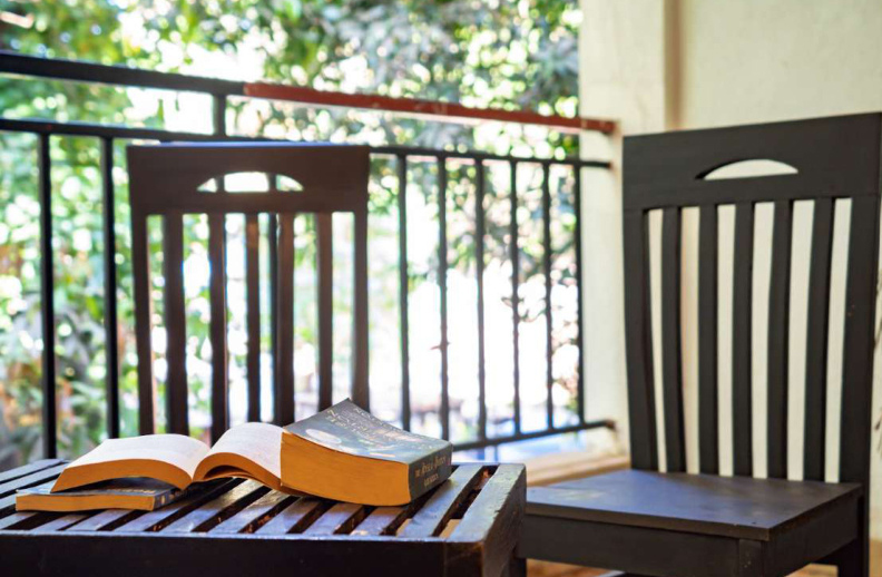 Cozy balcony reading corner with wooden chairs and books in Goa villa