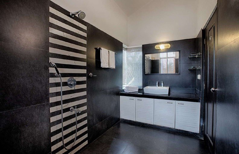Bathroom with shower area, white sink and black tiled walls