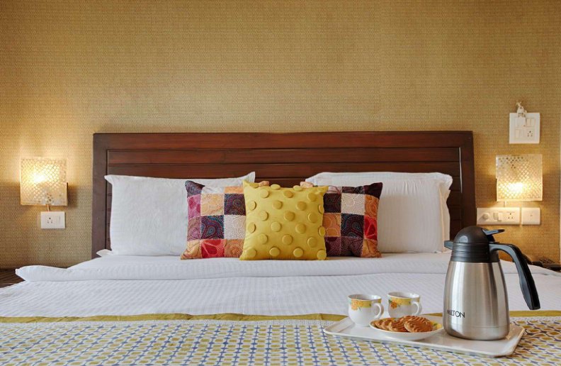 Bedroom with double bed, colorful cushions and tea set