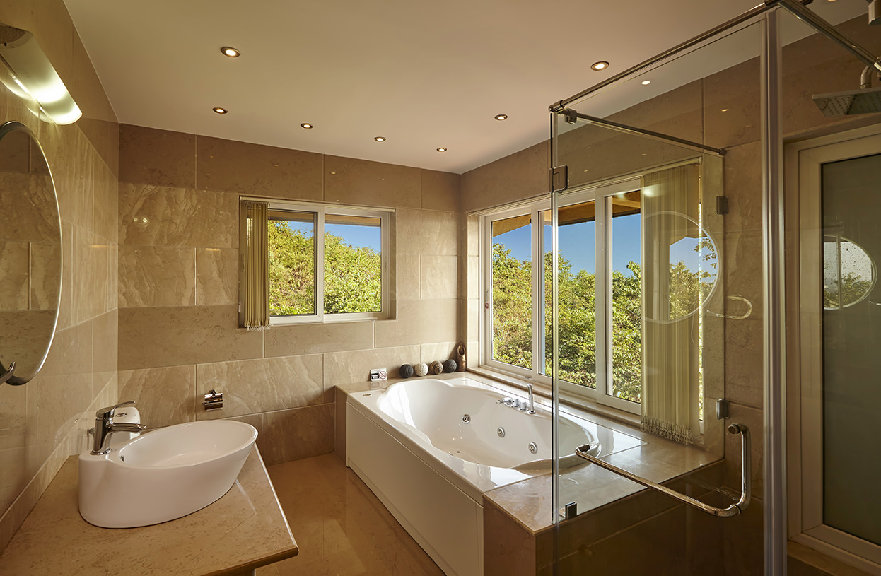 Luxurious bathroom with large jacuzzi tub, glass shower enclosure, and natural views from wide windows at Dolphin Heights