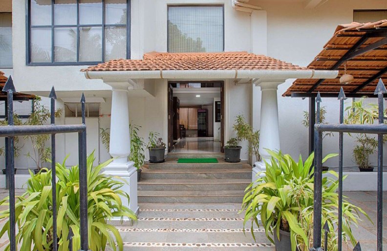 Villa entrance with tiled roof, steps and potted plants