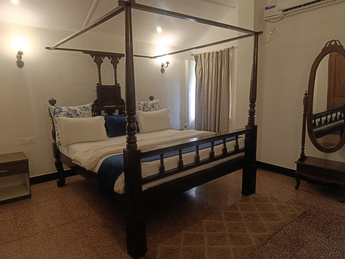 Bedroom with four-poster bed and patterned floor tiles.