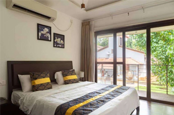 Modern bedroom with a king-size bed, balcony, and garden view