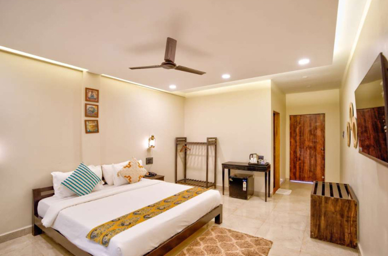 Modern bedroom interior with king bed, wooden furniture and warm lighting in Goa villa