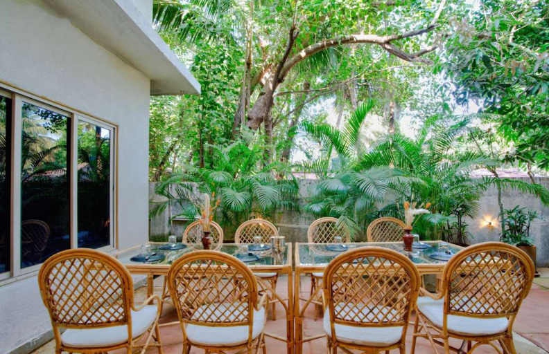 Outdoor garden dining area with rattan chairs in tropical Goa villa