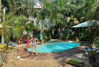 Backyard pool with tropical plants and children playing at Casa Da Praia villa