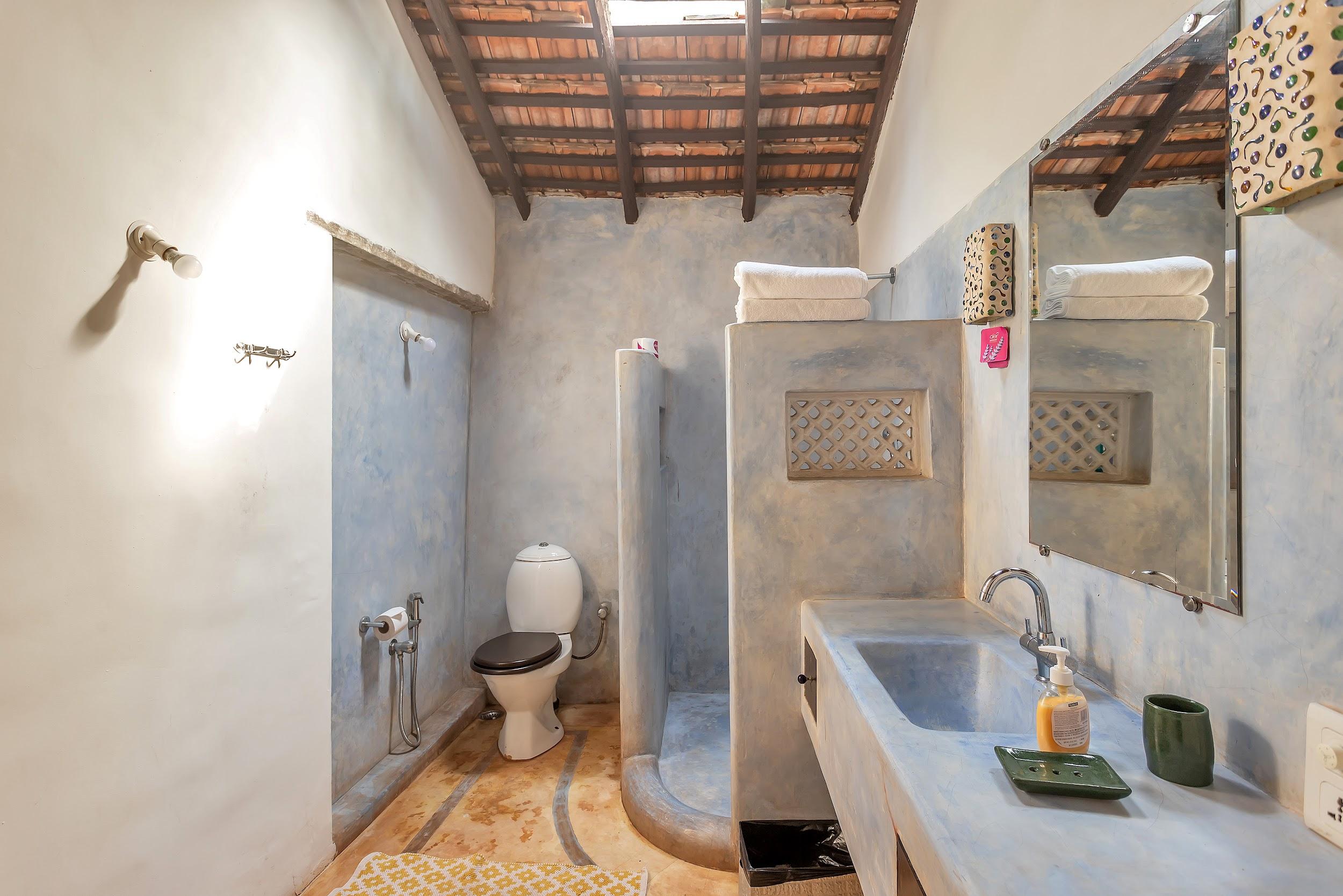 Bathroom with blue textured walls, exposed ceiling rafters, and a cement vanity