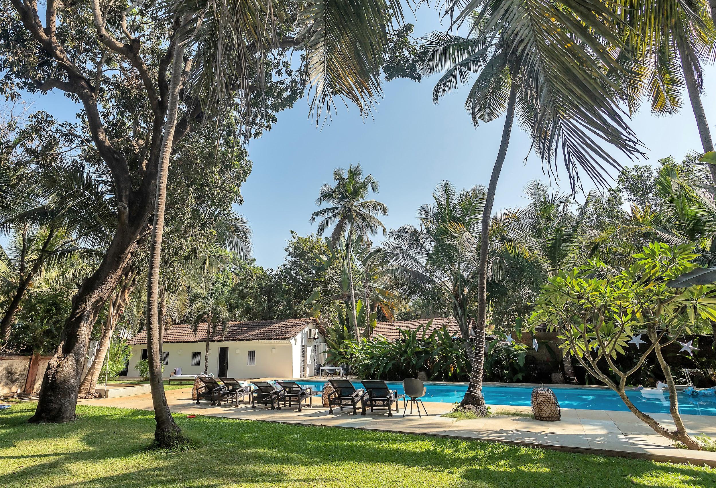 Sunny view across the lawn towards the white villa buildings and the bright blue pool