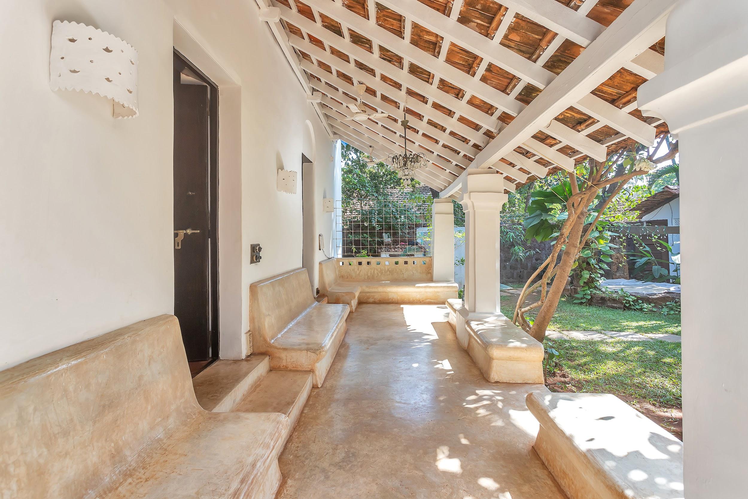 Covered outdoor veranda with white pillars and built-in, curved stone seating