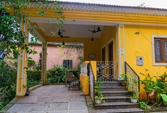 Yellow house with a front porch and garden at Goaround Portuguese Villa