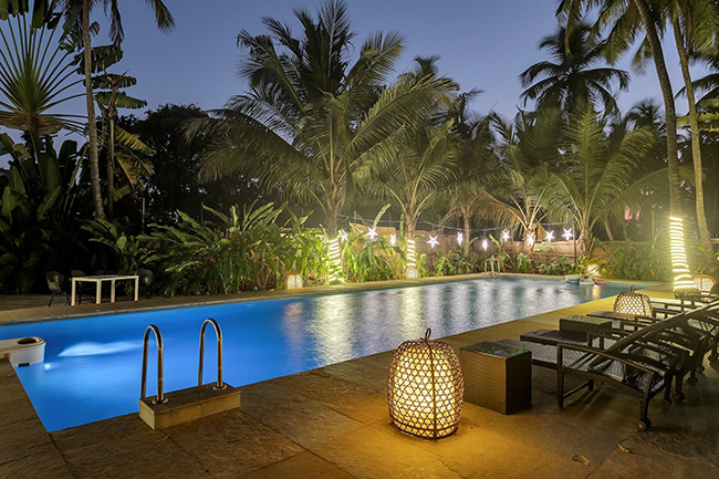 Private swimming pool with palm trees and loungers at night