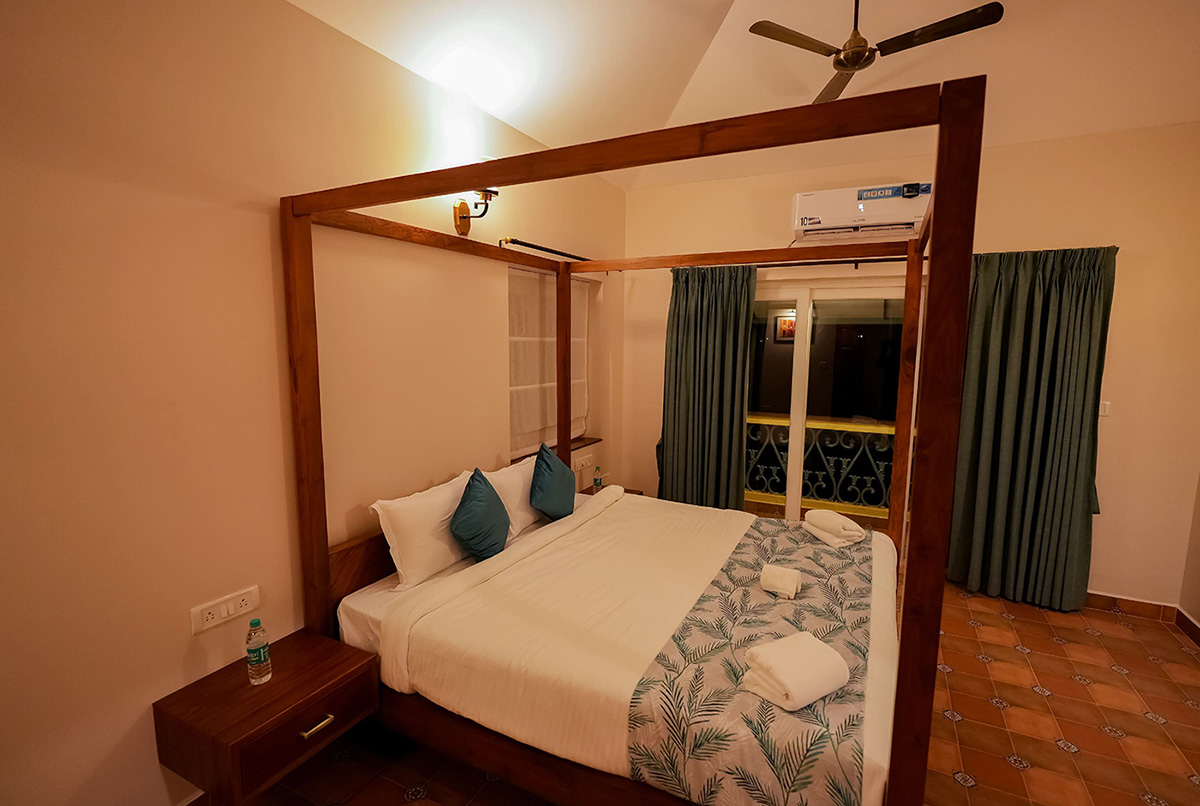 Bedroom with four-poster bed, blue accents, and large windows