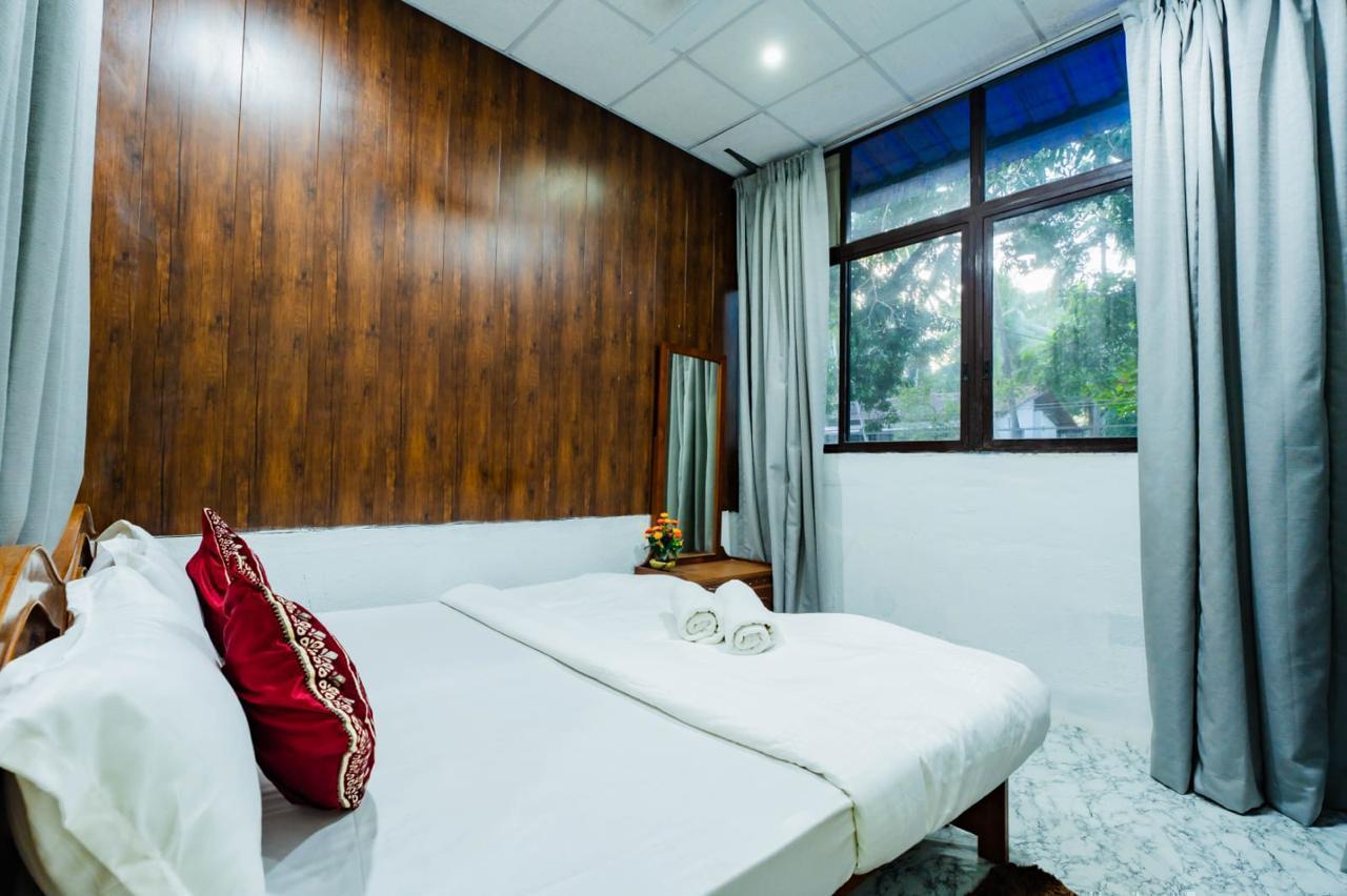 Bedroom with bed, wood-paneled wall, large window with gray curtains.
