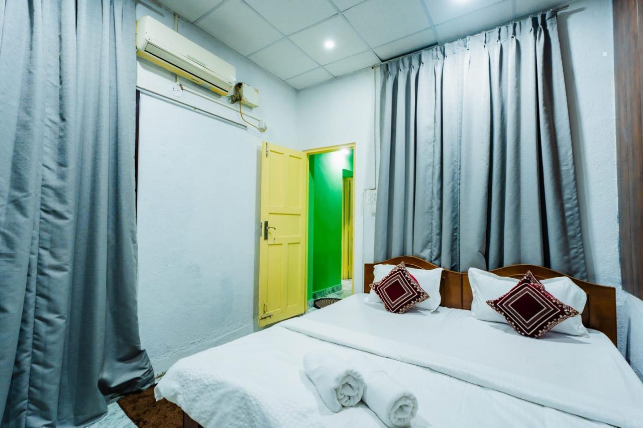  Bedroom with bed, yellow door to green room, gray curtains, and AC unit.