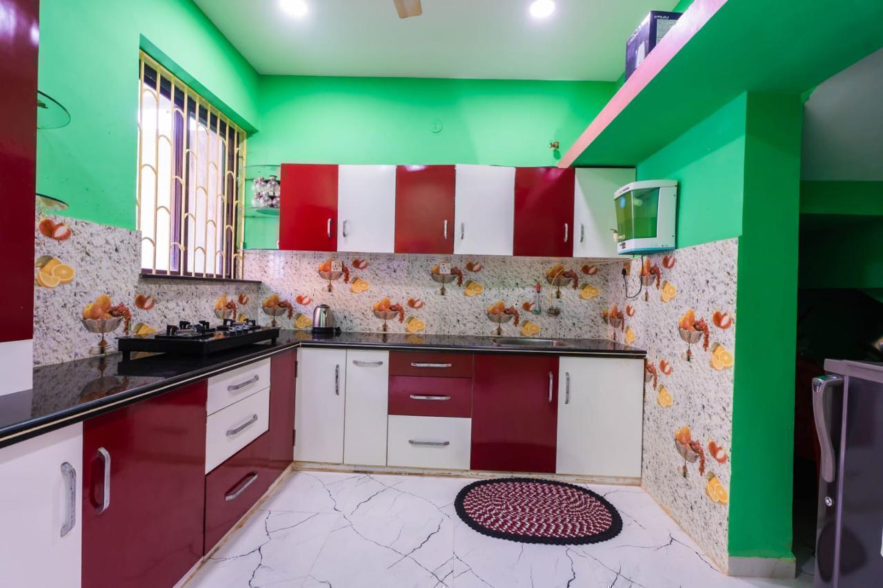 Kitchen with red/white cabinets, fruit-pattern tiles, mint green walls, and refrigerator.