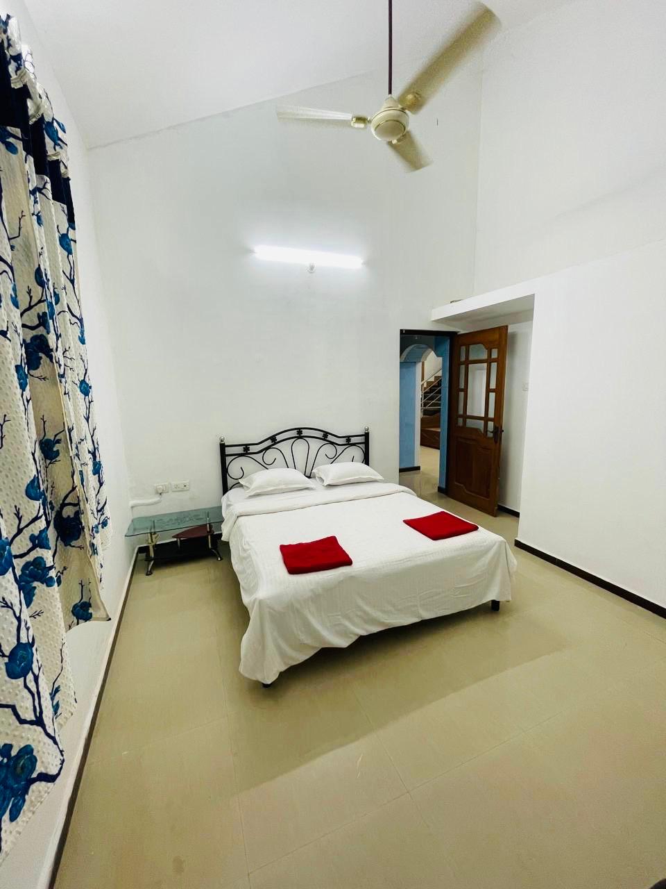 White bedroom with metal bed and ceiling fan.