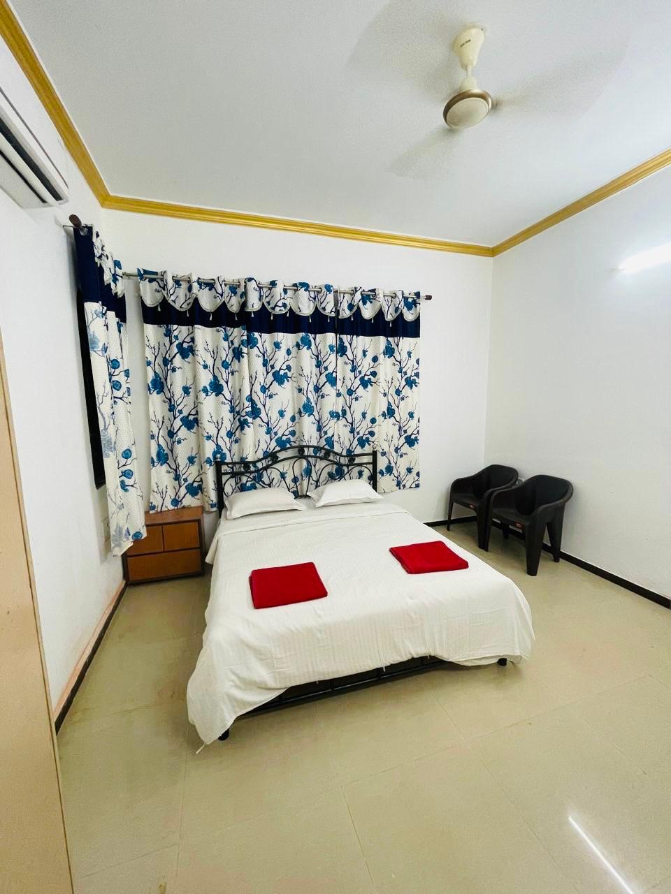 Bedroom with white bed, red towels, and floral curtains