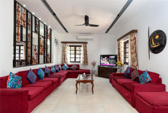 Spacious living room with red sofas, colorful cushions, and a TV