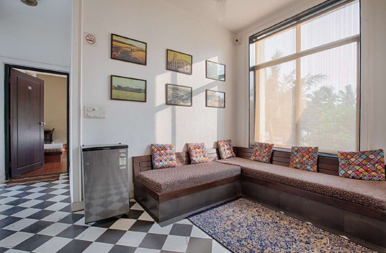 Villa seating area with cushioned sofa, large window and patterned rug