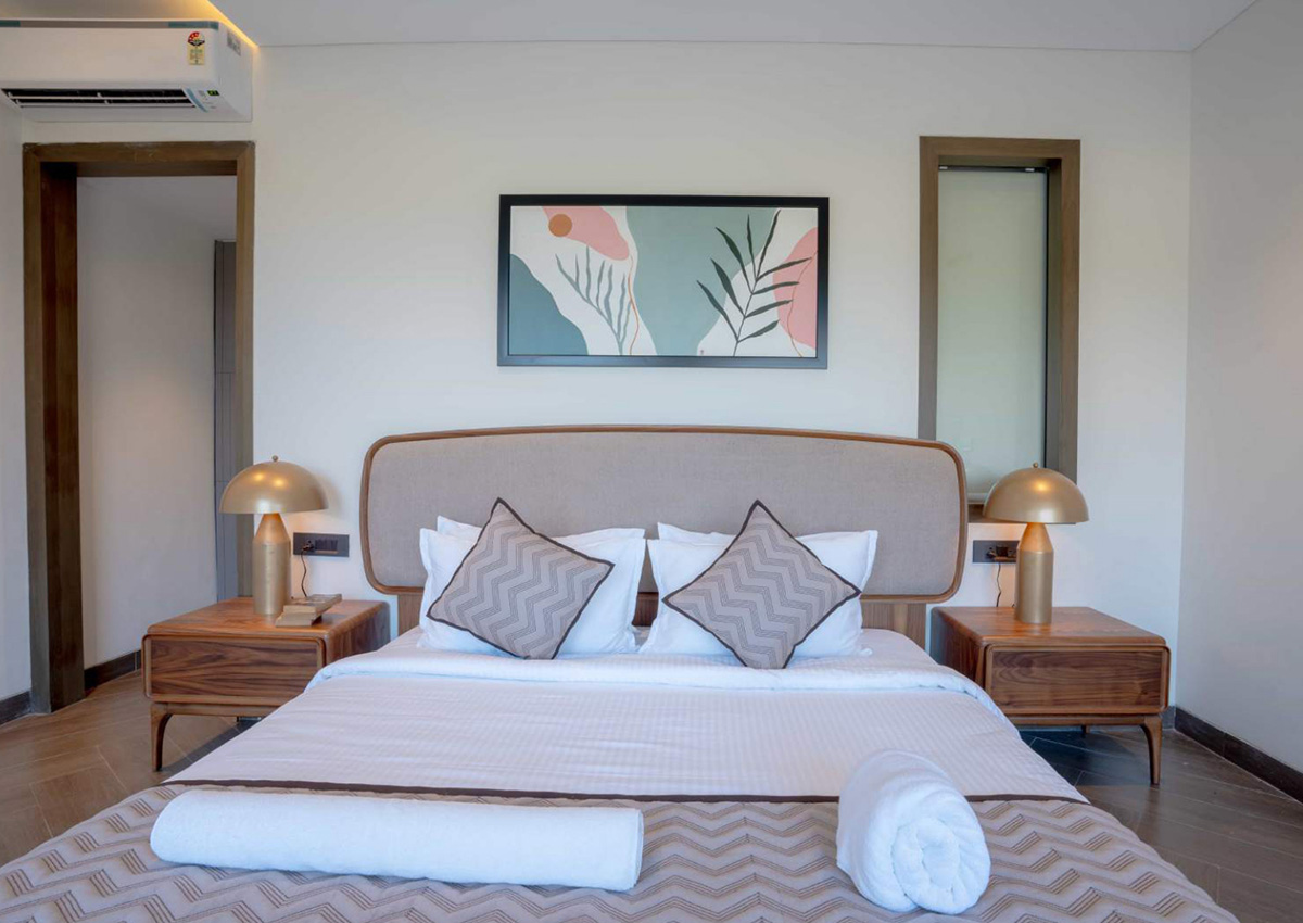 Close-up of double bed with beige headboard, zigzag cushions, and neatly arranged linens