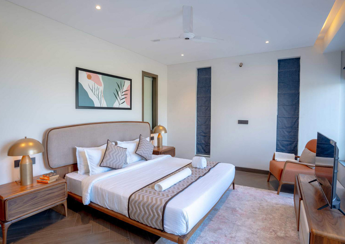 Cozy bedroom with beige upholstered bed, gold lamps, and warm wooden side tables
