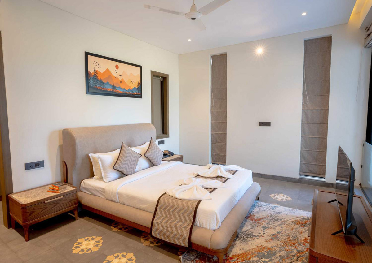 Bedroom featuring plush beige upholstered bed, wooden side tables, and soft lighting