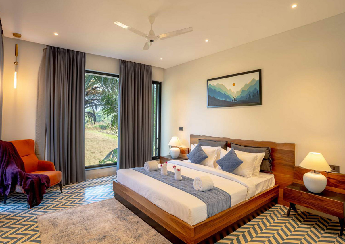 Blue-accent bedroom with large windows overlooking palm trees and open fields